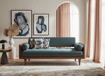 Blue Dori slub pillow on a teal sofa in a living room with framed portraits