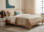 Teal Dori pillow on a bed with beige bedding in a calm bedroom