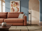 Grey slub print cushion on a rust sofa in a living room with abstract art