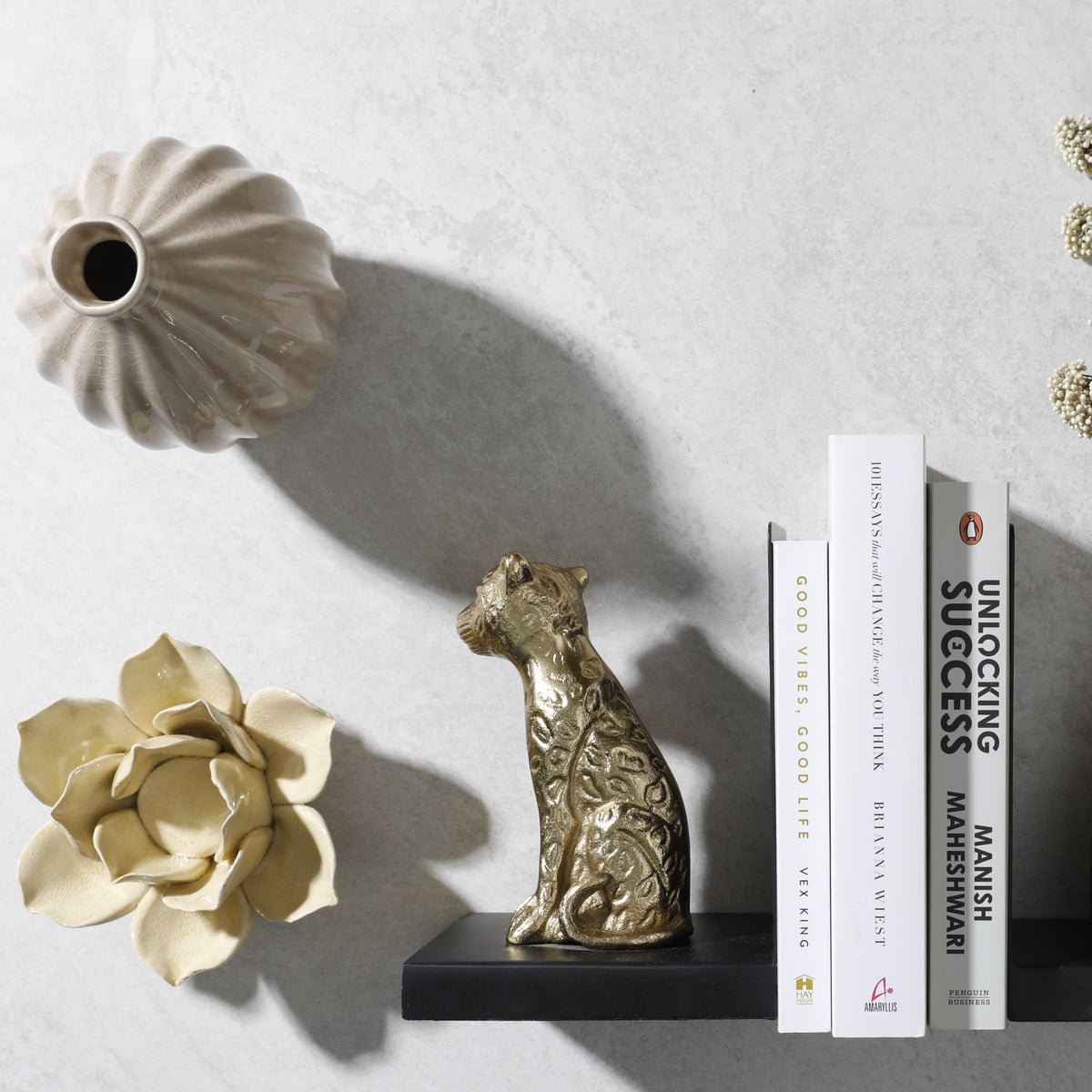 Gold leopard bookend with books, a ceramic vase and a gold lotus on a shelf