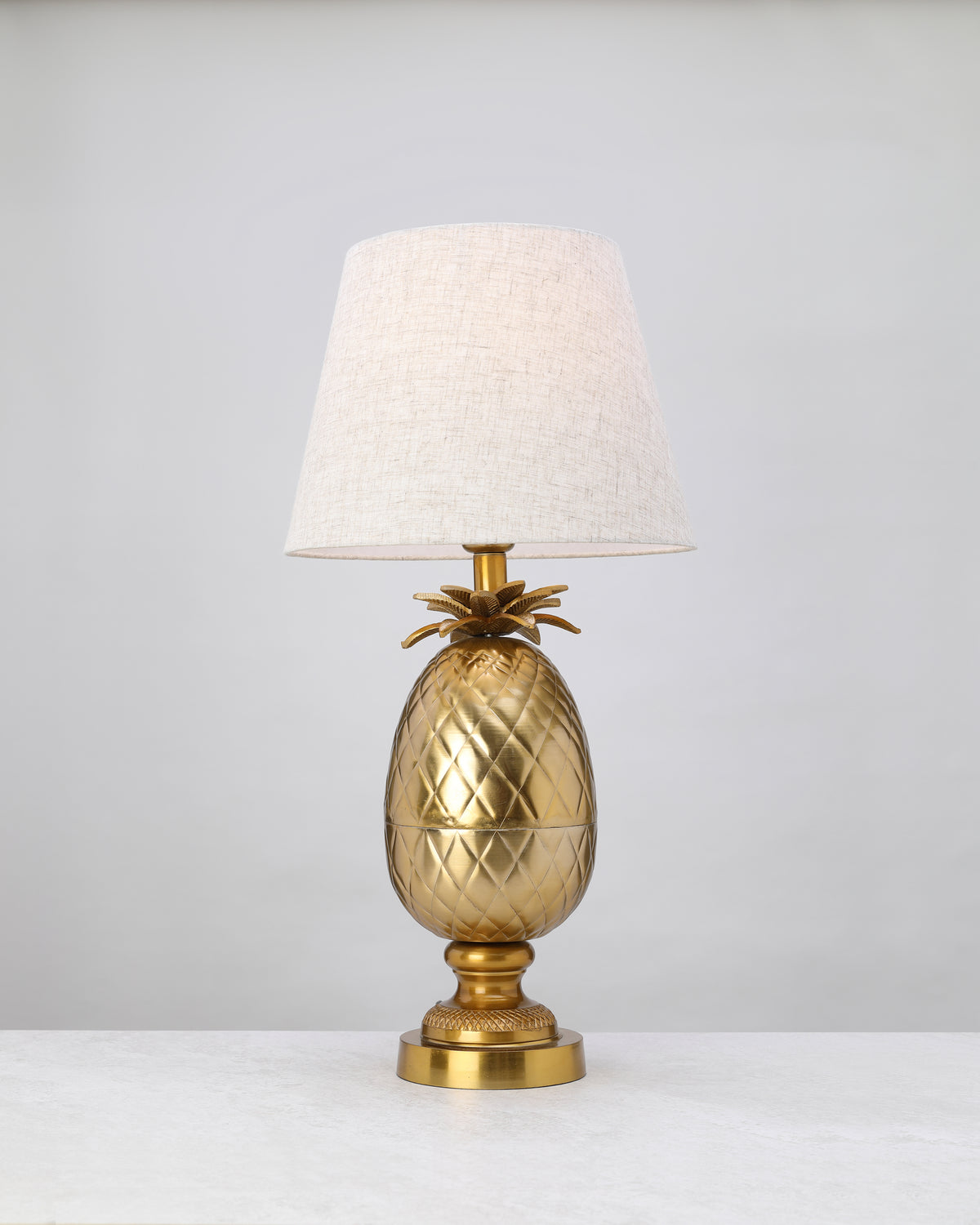 Antique brass pineapple lamp base styled with a linen shade (shade not included)