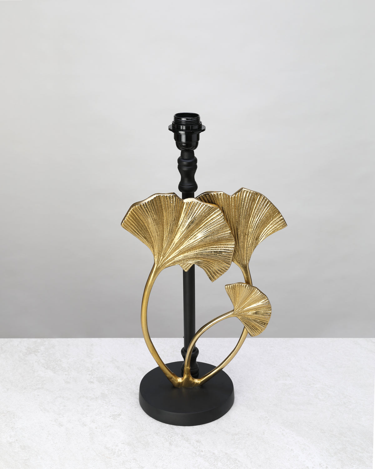 Gilded ginkgo leaf table lamp base on a black stand, shown without a shade