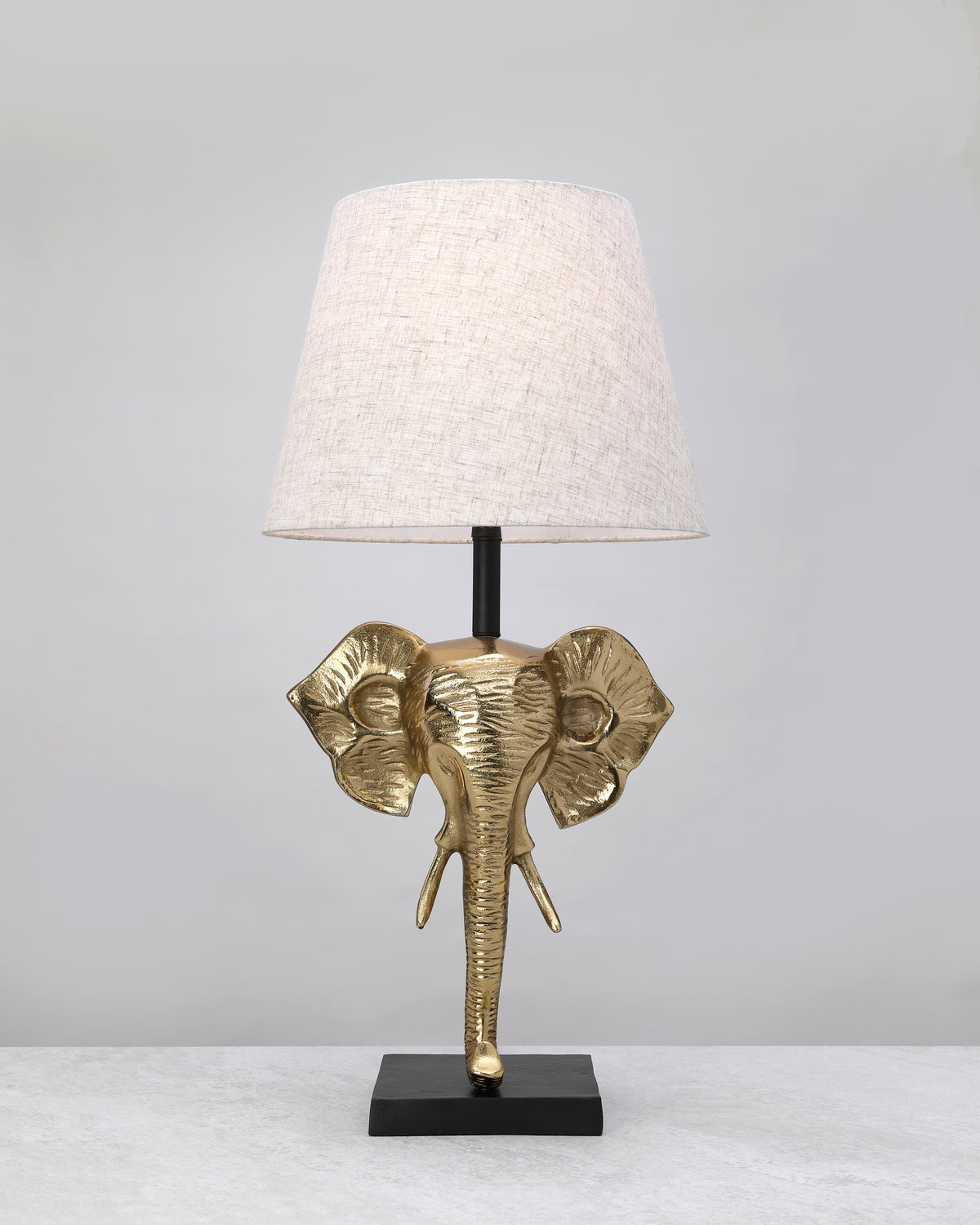 Gilded elephant head lamp base styled with a linen shade (shade not included)