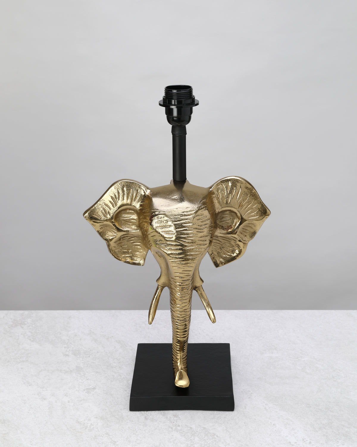 Gilded elephant head table lamp base on a black square stand, shown without a shade