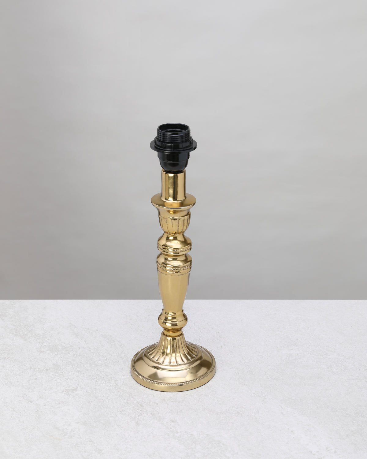Slender gilded column table lamp base in polished gold, shown without a shade