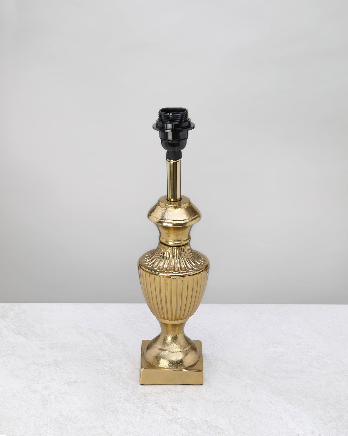 Slim gold reed table lamp base with a fluted urn shape, shown without a shade