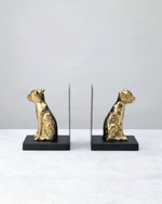 Pair of gold leopard bookends on black bases facing each other, on white