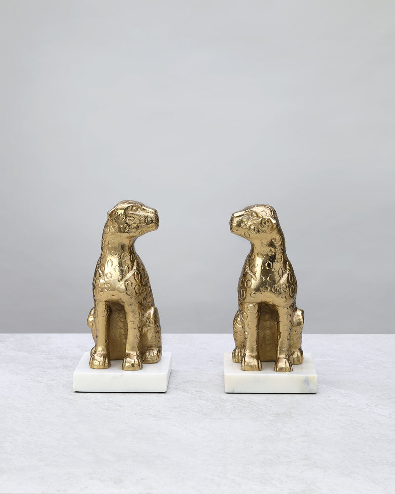 Pair of seated gold leopard bookends on white marble bases, front view