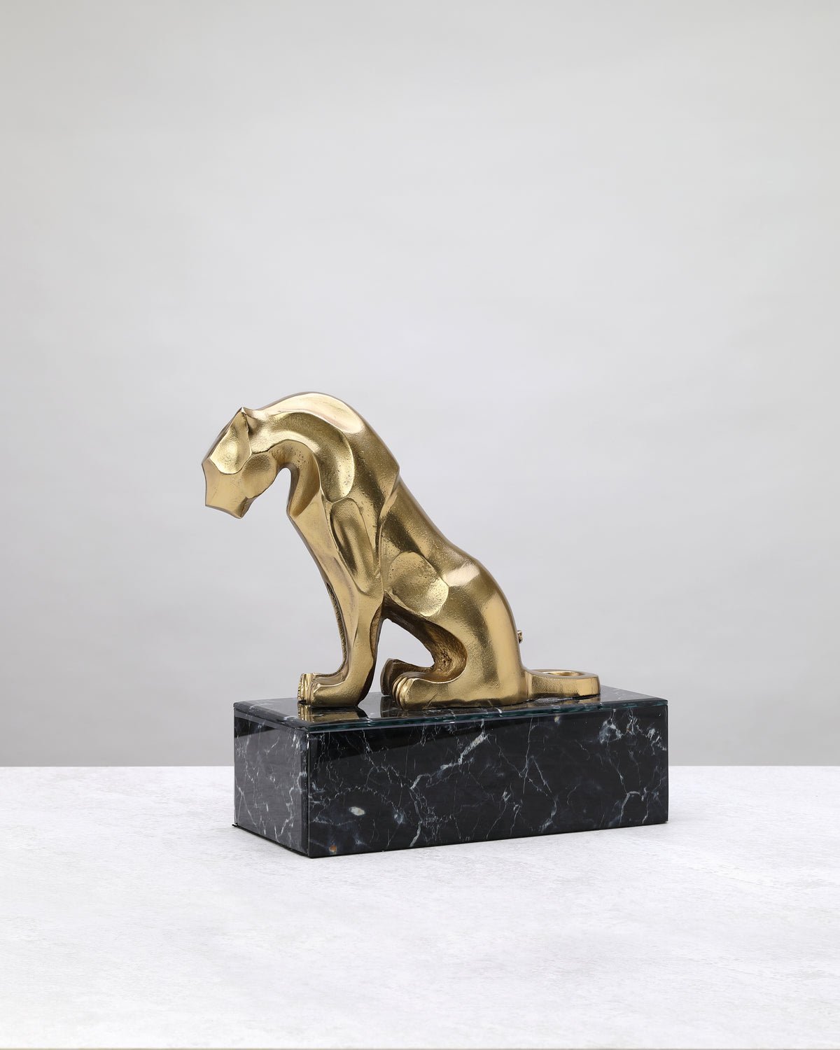 Tall gold lion on its marble-finish base, side view showing the sculpted body