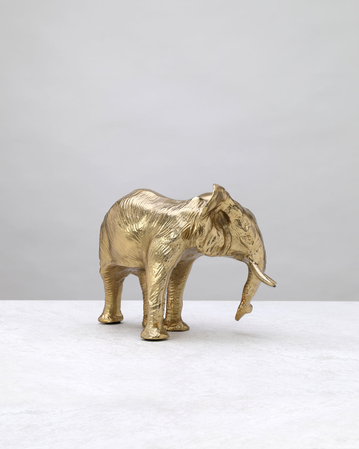 Wide-base gold elephant figure from the other side, showing its tusks