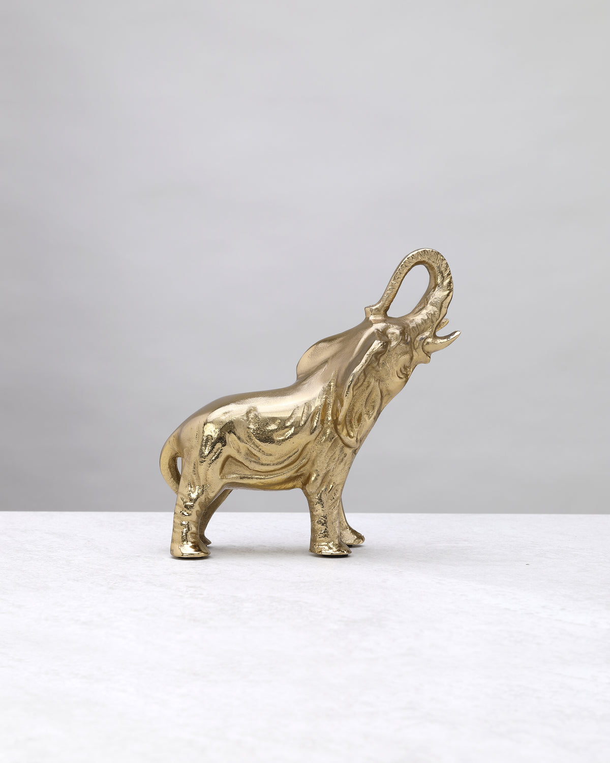 Petite gold elephant figure from the other side, trunk curled upward
