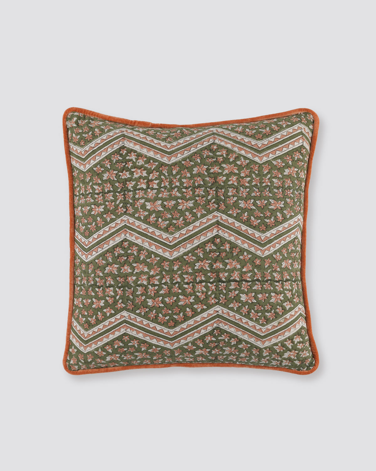 Orange piped cushion cover with a green zigzag block print and rust piping, front view