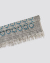 Teal block print cotton dhurrie rug folded to show the pattern and fringed ends