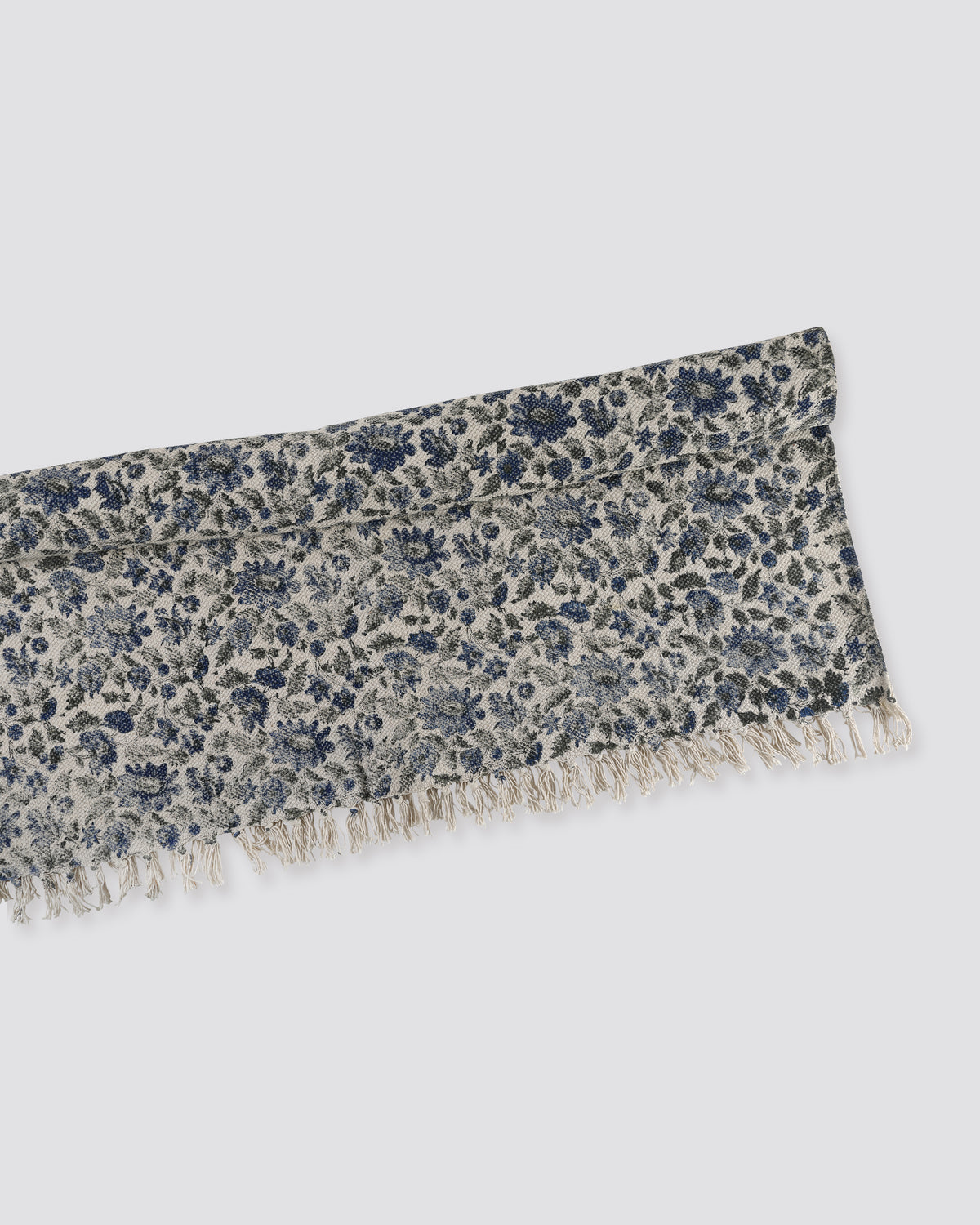 Blue block print cotton dhurrie rug folded, showing the floral print and fringe