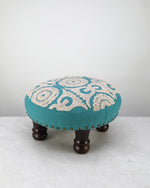 Teal round foot stool with a cream embroidered medallion top on turned wooden legs