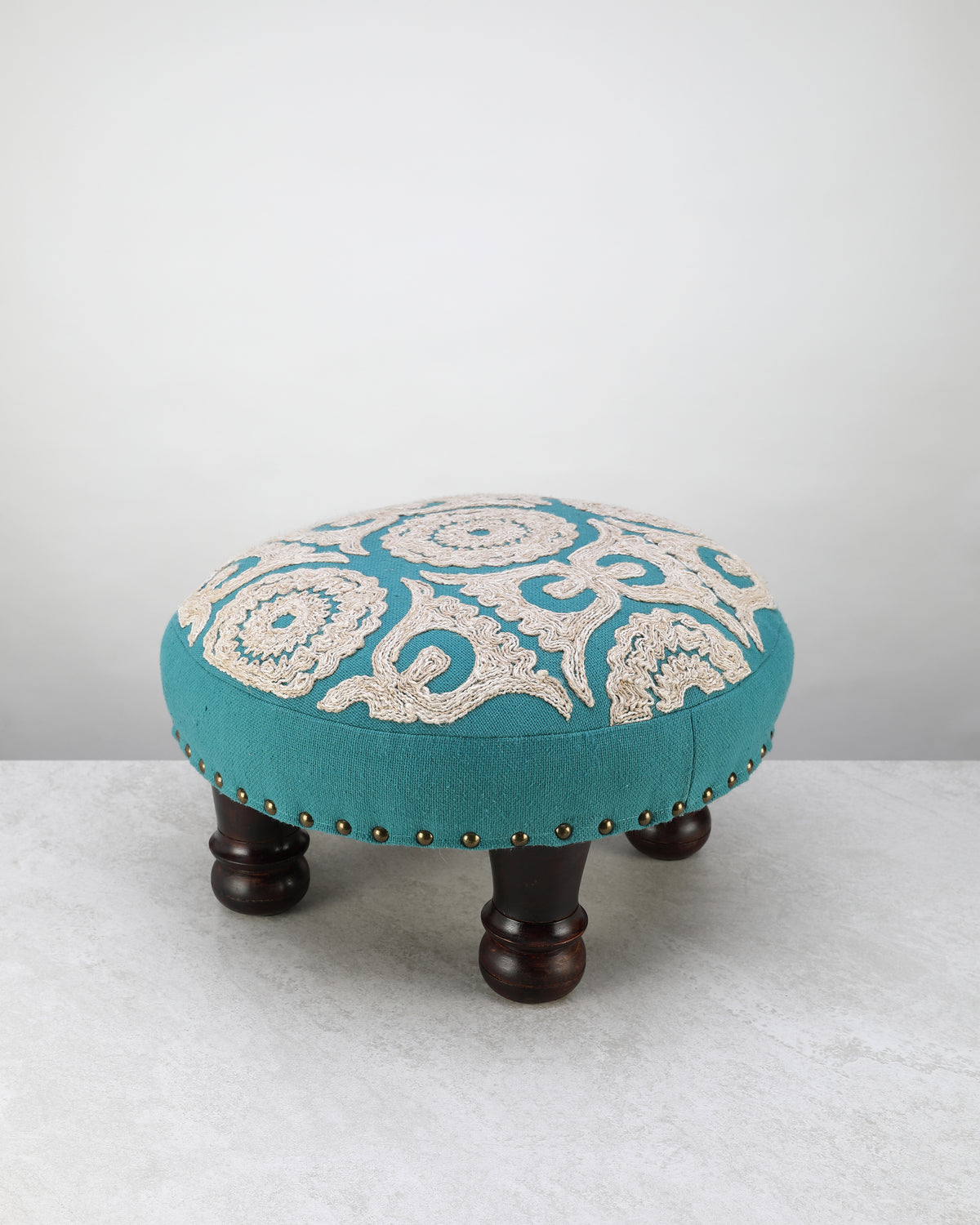 Teal round foot stool with a cream embroidered medallion top on turned wooden legs
