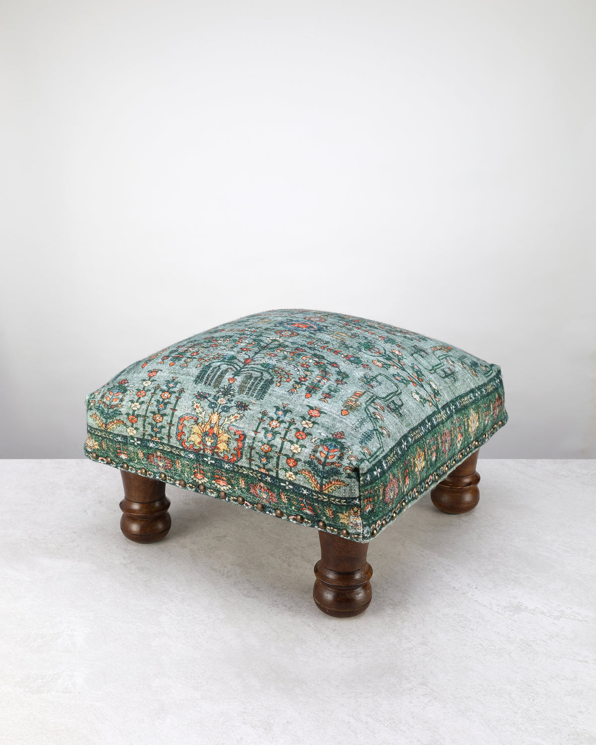 Green and teal printed square foot stool on turned wooden legs, on white