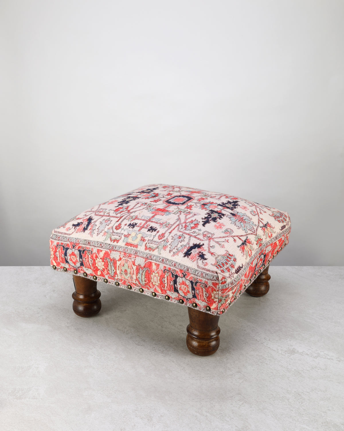 Red and pink printed square foot stool on turned wooden legs, on white