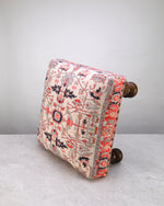 Red print square foot stool on its side, showing the printed fabric and legs