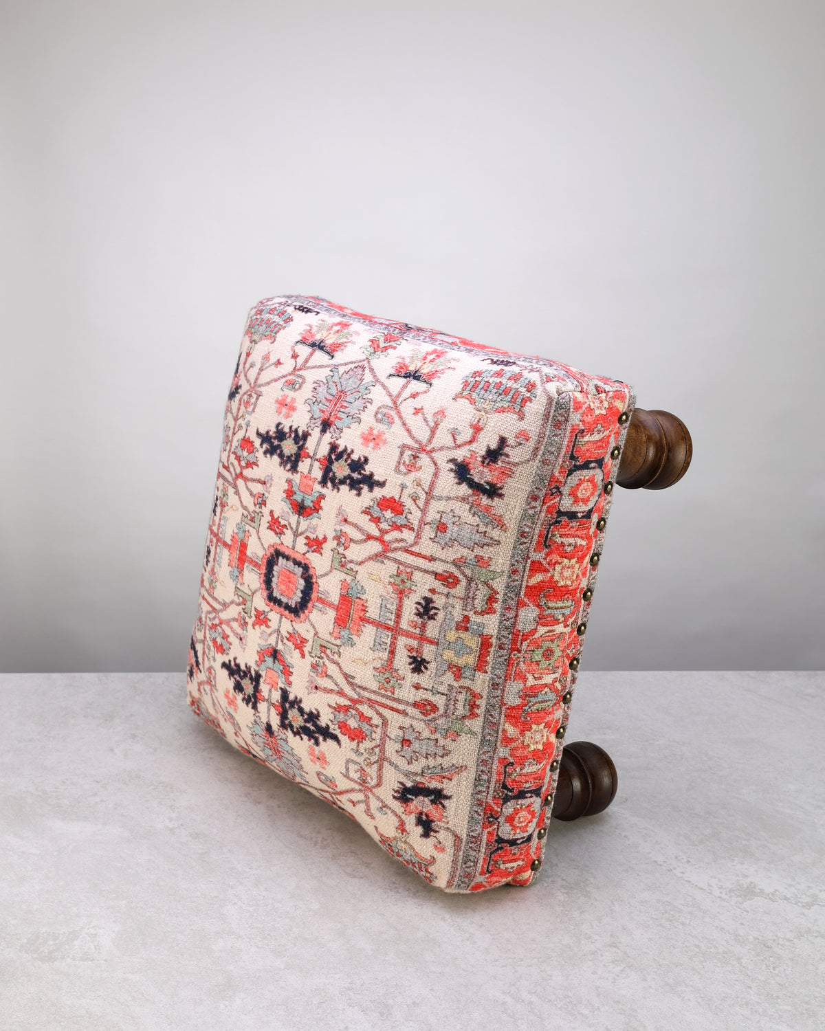 Red print square foot stool on its side, showing the printed fabric and legs