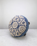 Blue Dori foot stool on its side showing the embroidered top
