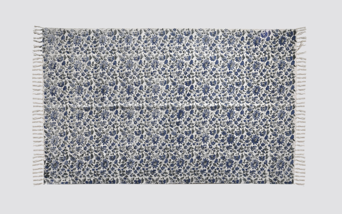Blue and white block print dhurrie rug laid flat with an all-over floral pattern