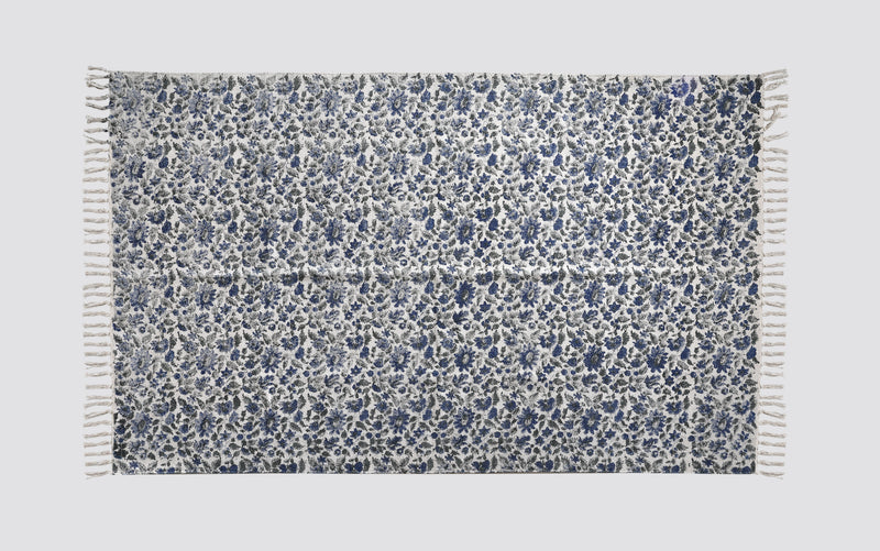 Blue and white block print dhurrie rug laid flat with an all-over floral pattern