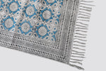 Corner of the teal block print dhurrie showing the border and tasselled fringe