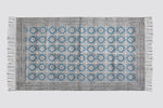 Teal and grey block print dhurrie rug laid flat with a tile pattern and fringe, top view
