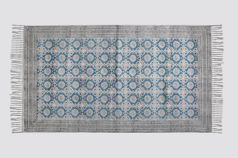 Teal and grey block print dhurrie rug laid flat with a tile pattern and fringe, top view
