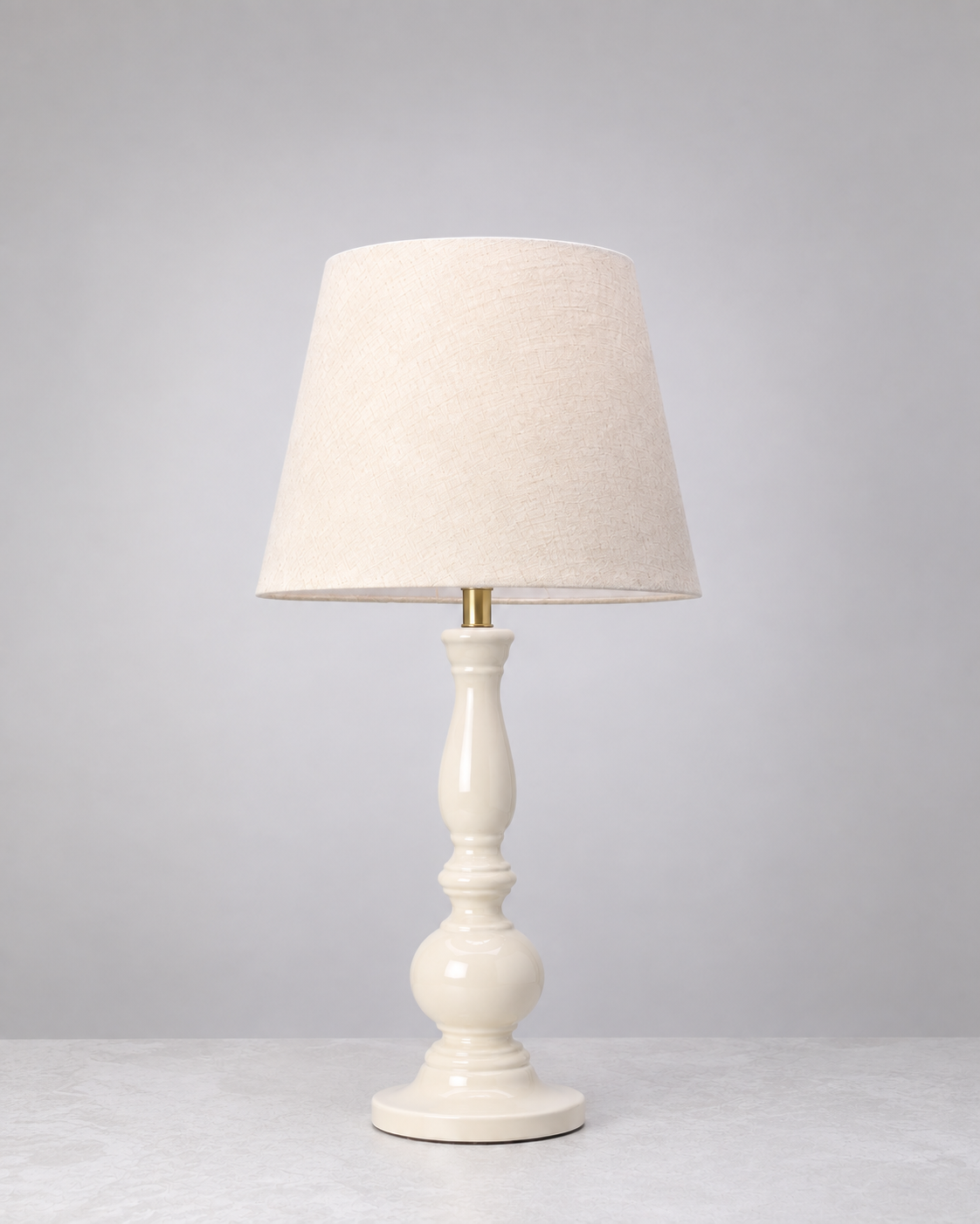 Warm white Dusk mango wood table lamp with a tall turned base and linen shade, on white