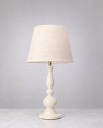 Warm white Dusk mango wood table lamp with a tall turned base and linen shade, on white