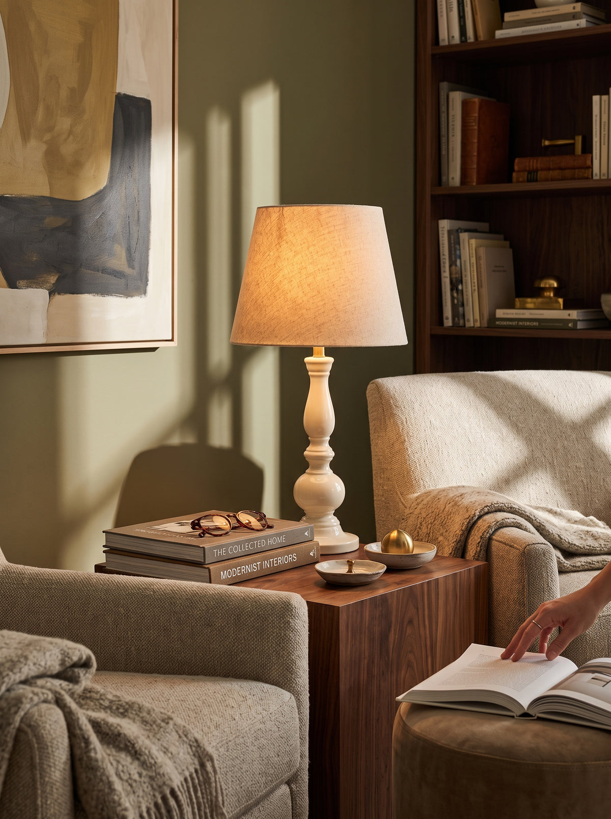 Warm white Dusk mango wood table lamp lit on a side table in a reading corner with books
