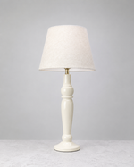 Warm white Sunlit mango wood table lamp with a turned base and linen shade, on white