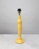 Yellow turned mango wood lamp base shown without its shade