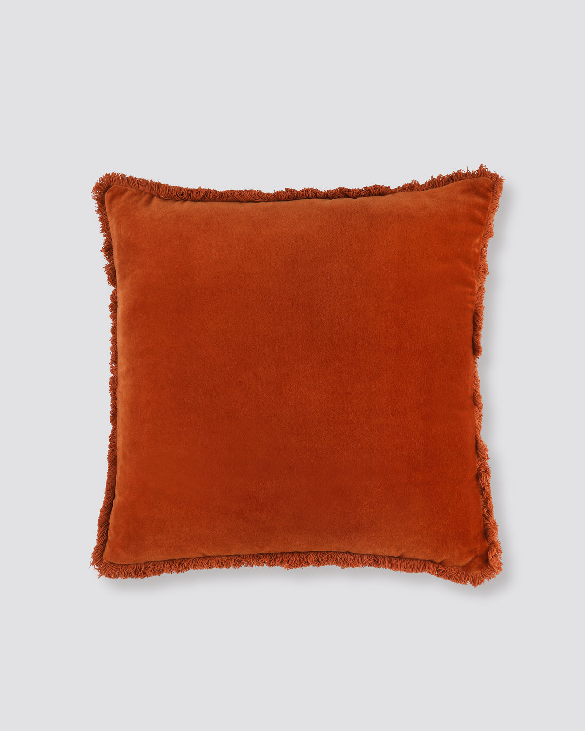 Rust square velvet cushion cover with a fringed edge on all four sides, front view