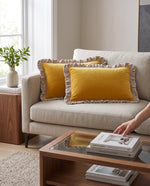 Hand arranging mustard frill velvet cushions on a cream sofa