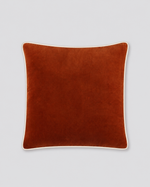 Rust velvet cushion cover with cream piping around the edge, front view