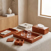Tan faux leather tissue box with matching trays and coasters on a coffee table