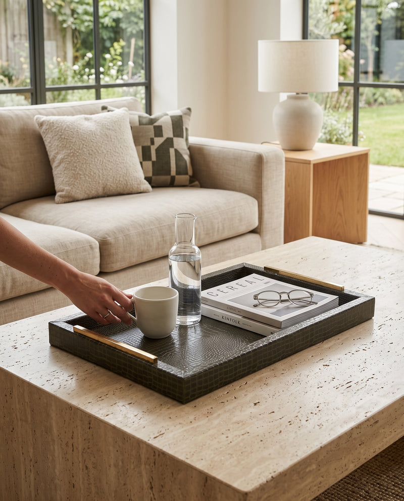 Hand setting a drink on the olive green slim tray on a coffee table