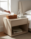 Tan faux leather tissue box on a bedside table, a hand pulling a tissue