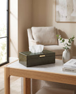 Olive green faux leather tissue box on a side table beside an armchair