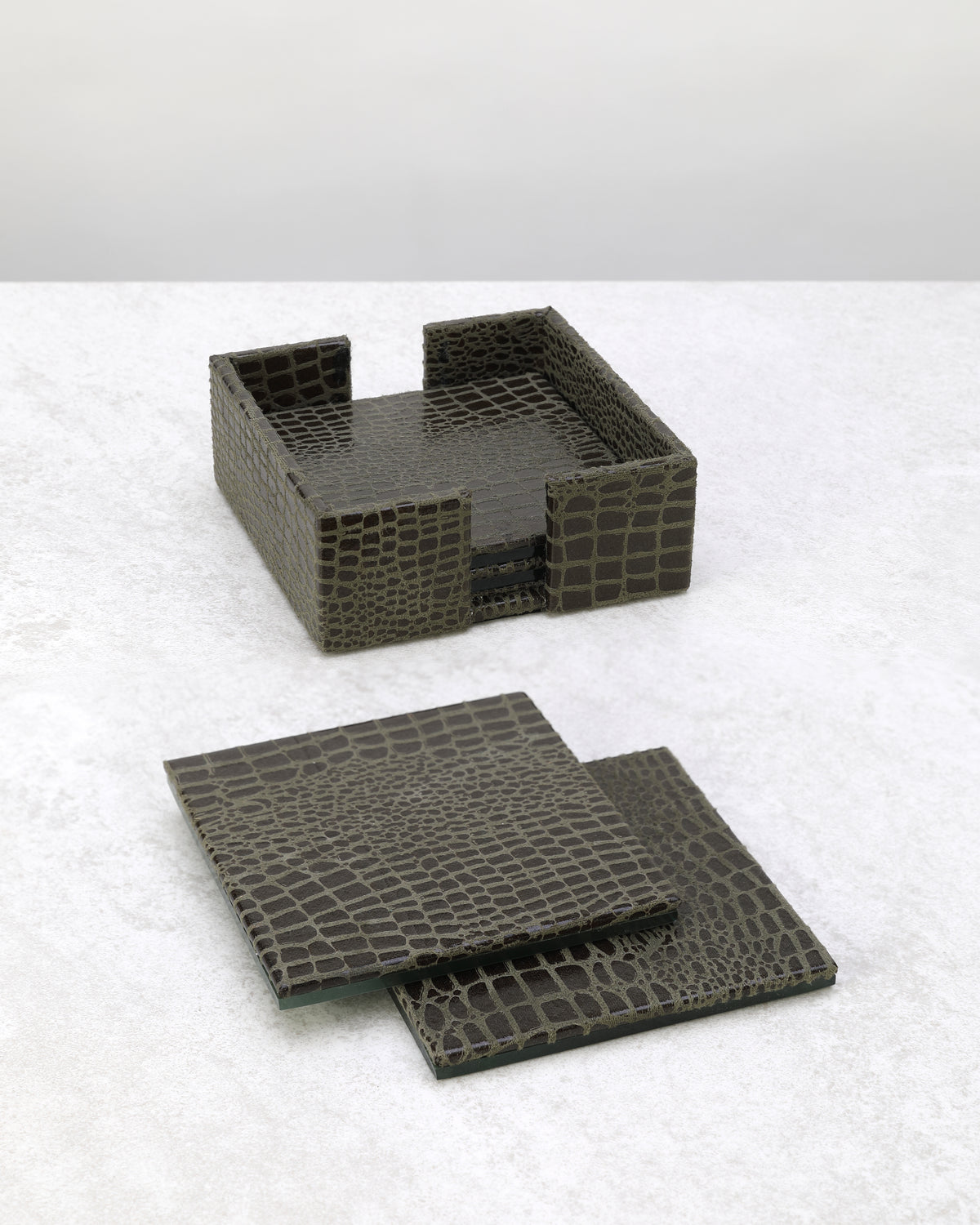 Olive green slim faux leather coasters laid out beside their holder