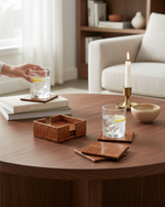 Hand setting a glass on a tan faux leather coaster on a round wooden table