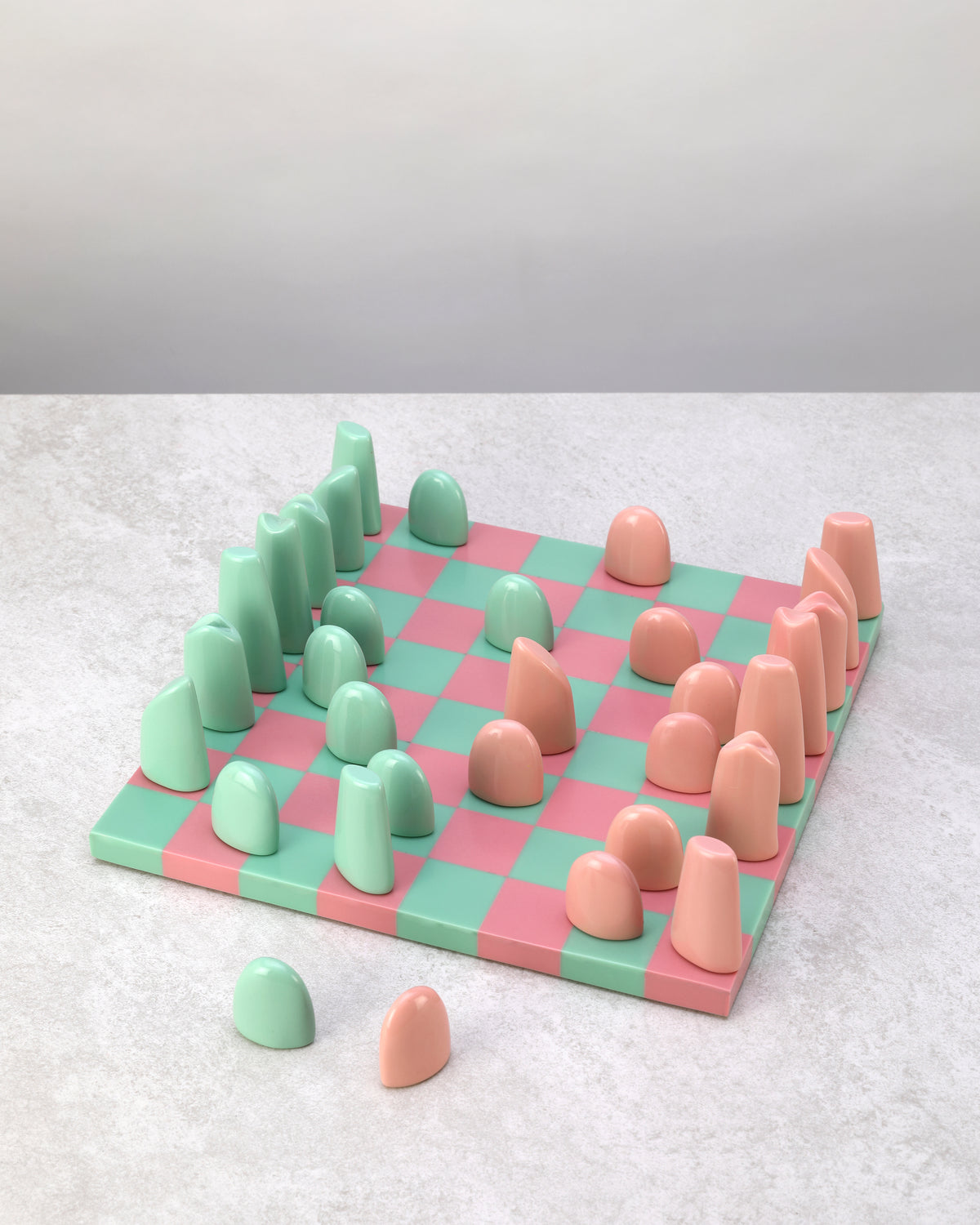 Pink and mint resin chess set laid out ready to play, pieces in two rows each side