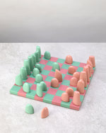 Pink and mint resin chess set laid out ready to play, pieces in two rows each side