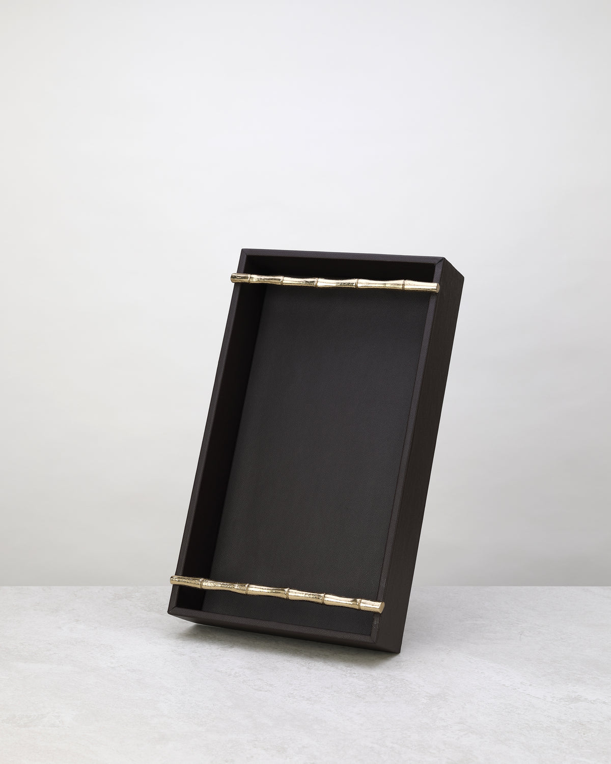 Small cherry faux leather tray standing upright to show its brass bar handles