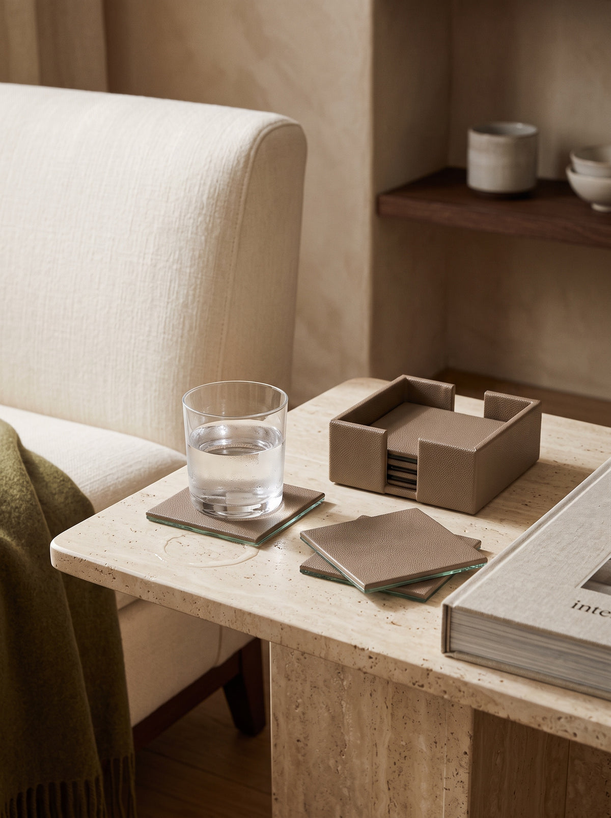 Pea green faux leather coasters and holder on a marble side table beside a glass