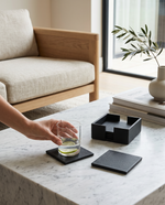 Hand setting a glass on an olive green faux leather coaster on a coffee table