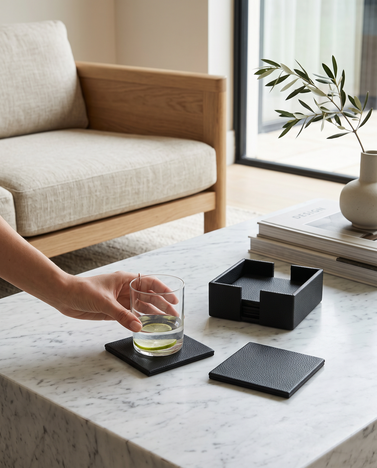 Hand setting a glass on an olive green faux leather coaster on a coffee table